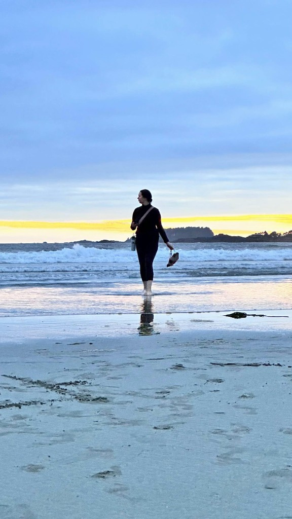 Person walking barefoot on a beach at dusk
