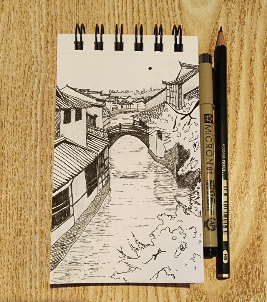 Ink sketch of a canal town with an arched bridge in a spiral notebook